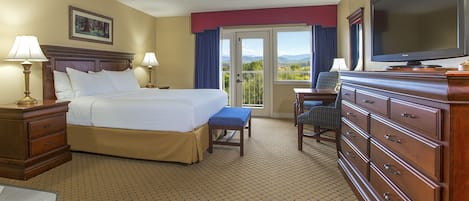 A hotel room with a bed, a dresser, a television, and a view of the outdoors.