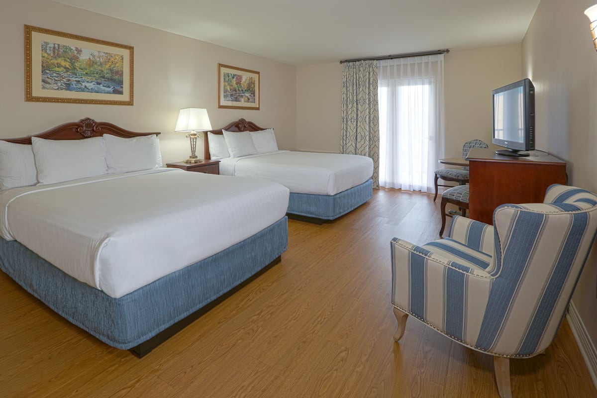 Quarto de hotel com duas camas, televisão, escrivaninha e uma cadeira.