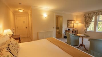 Habitación de hotel con cama, escritorio, silla, lámpara y ventana con cortinas.