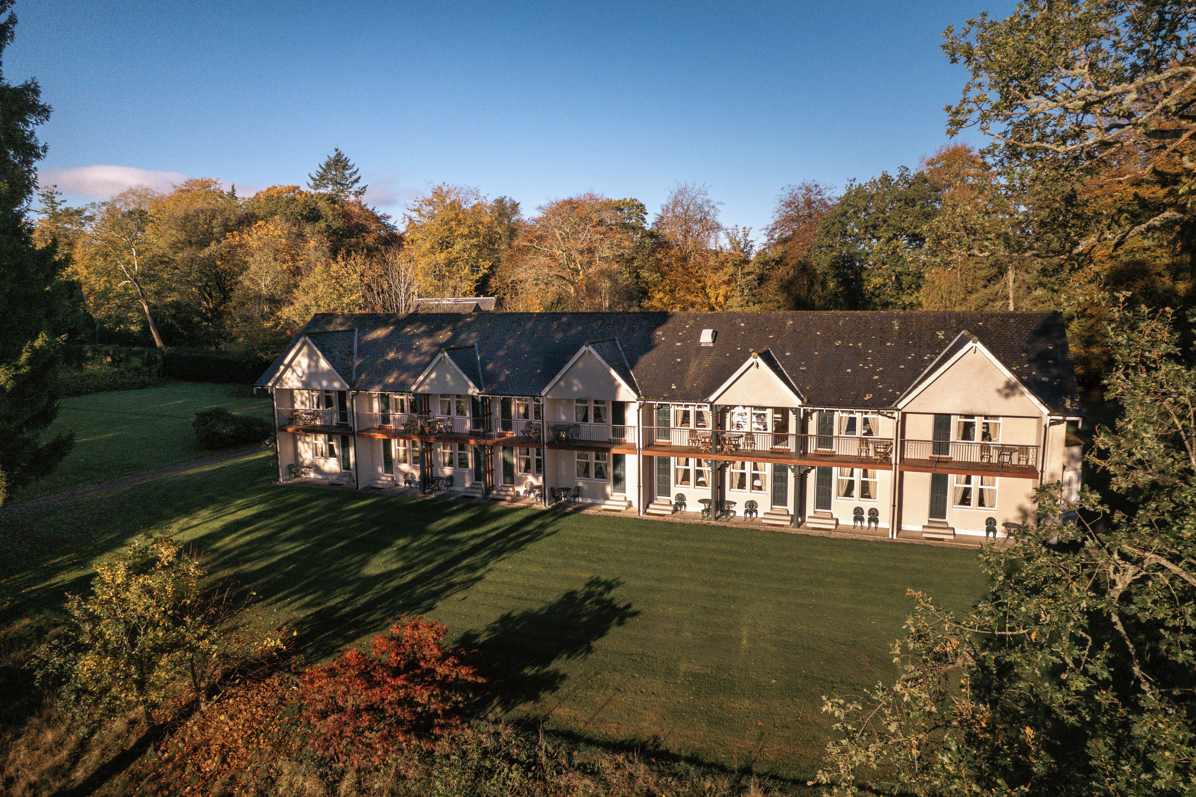 A large, multi-story building with a symmetrical facade, multiple balconies, and a well-maintained lawn.