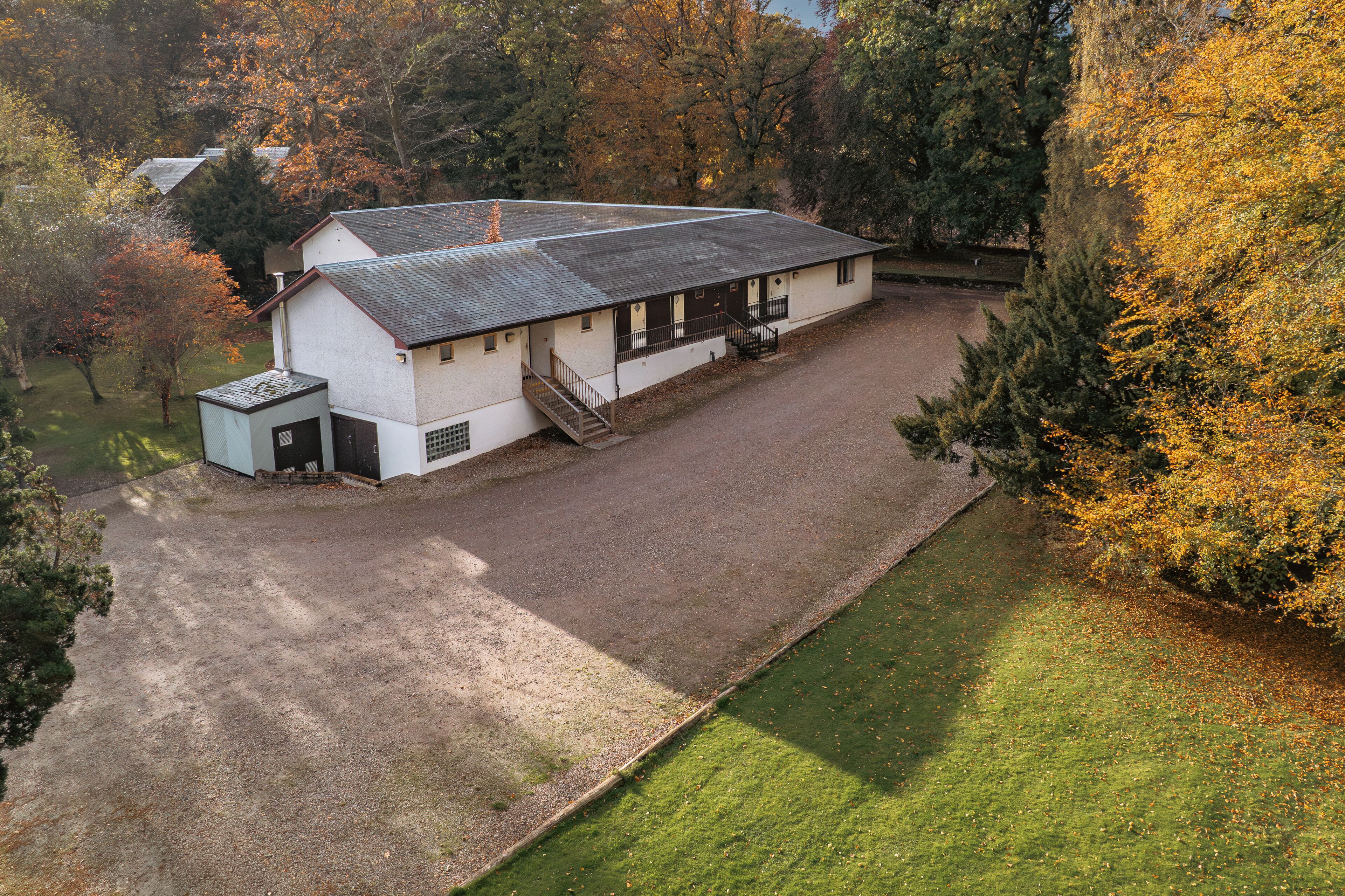 A single-story building with a sloped roof, a small attached garage, and a paved driveway.