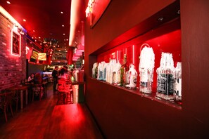 A bar area with wooden tables and chairs, a counter with bottles, and a red-lit wall. - Brunswick Merchant City Hotel (Glasgow)