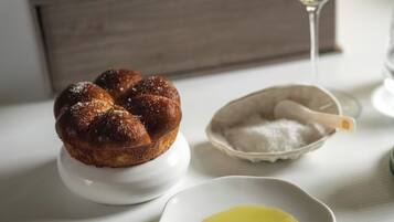 A dessert on a white plate, a small bowl of sugar, and a glass of white wine on a table.