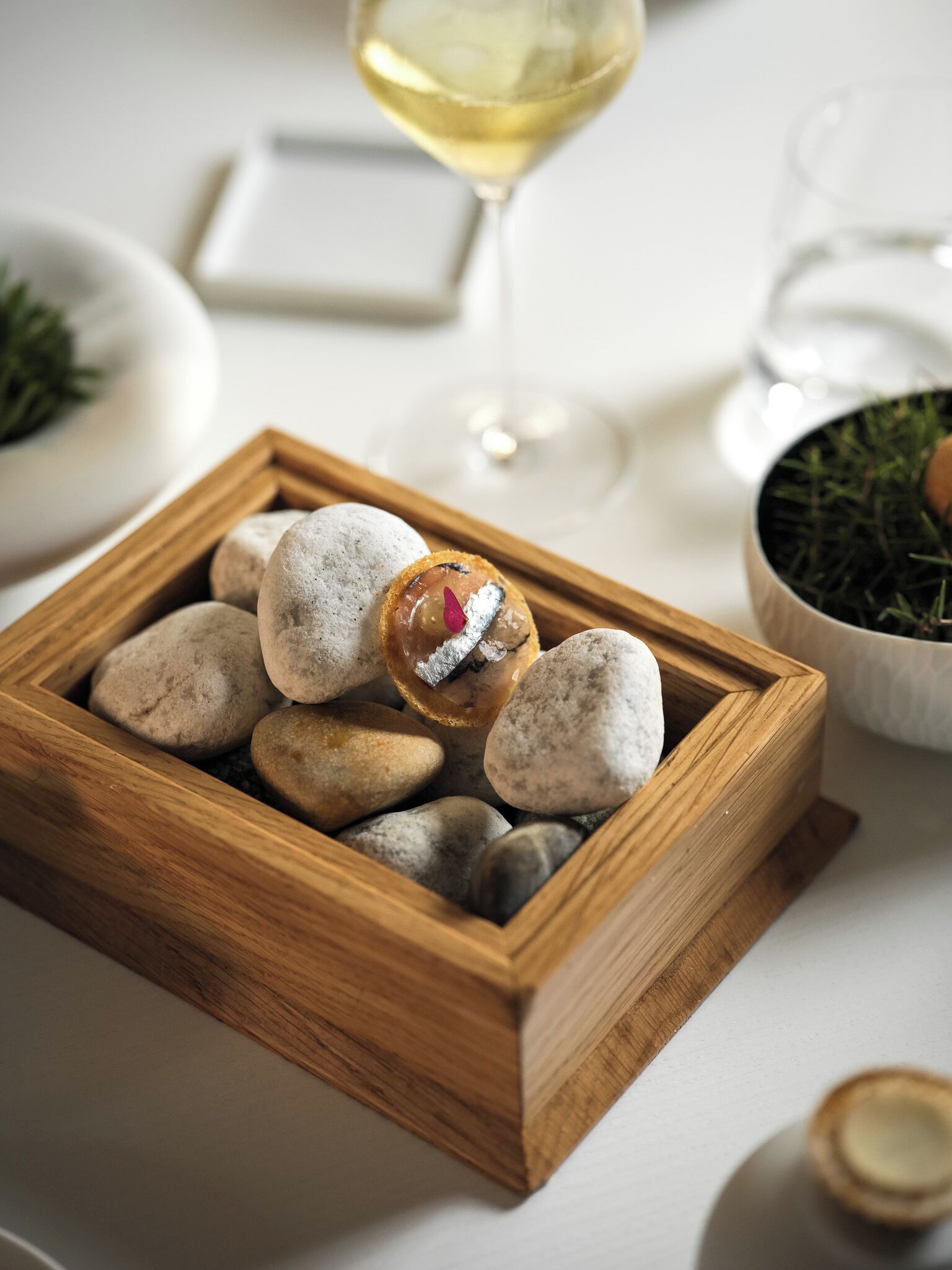 A wooden tray with smooth stones and a small decorative item.