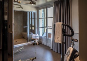 Un baño moderno con cabina de ducha de vidrio, un perchero para toallas y una bicicleta estática.