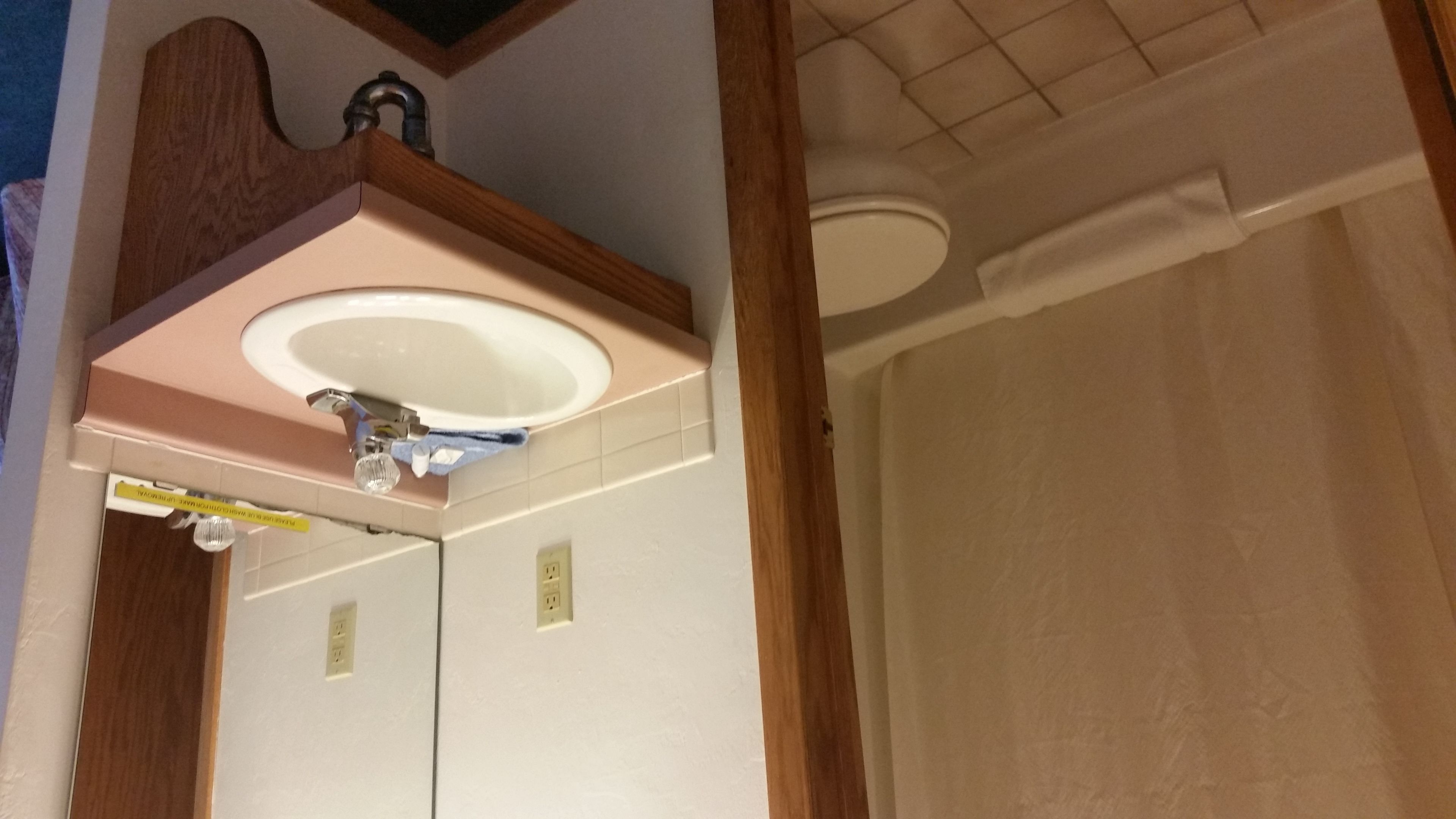 A bathroom with a sink, mirror, and a shower area.