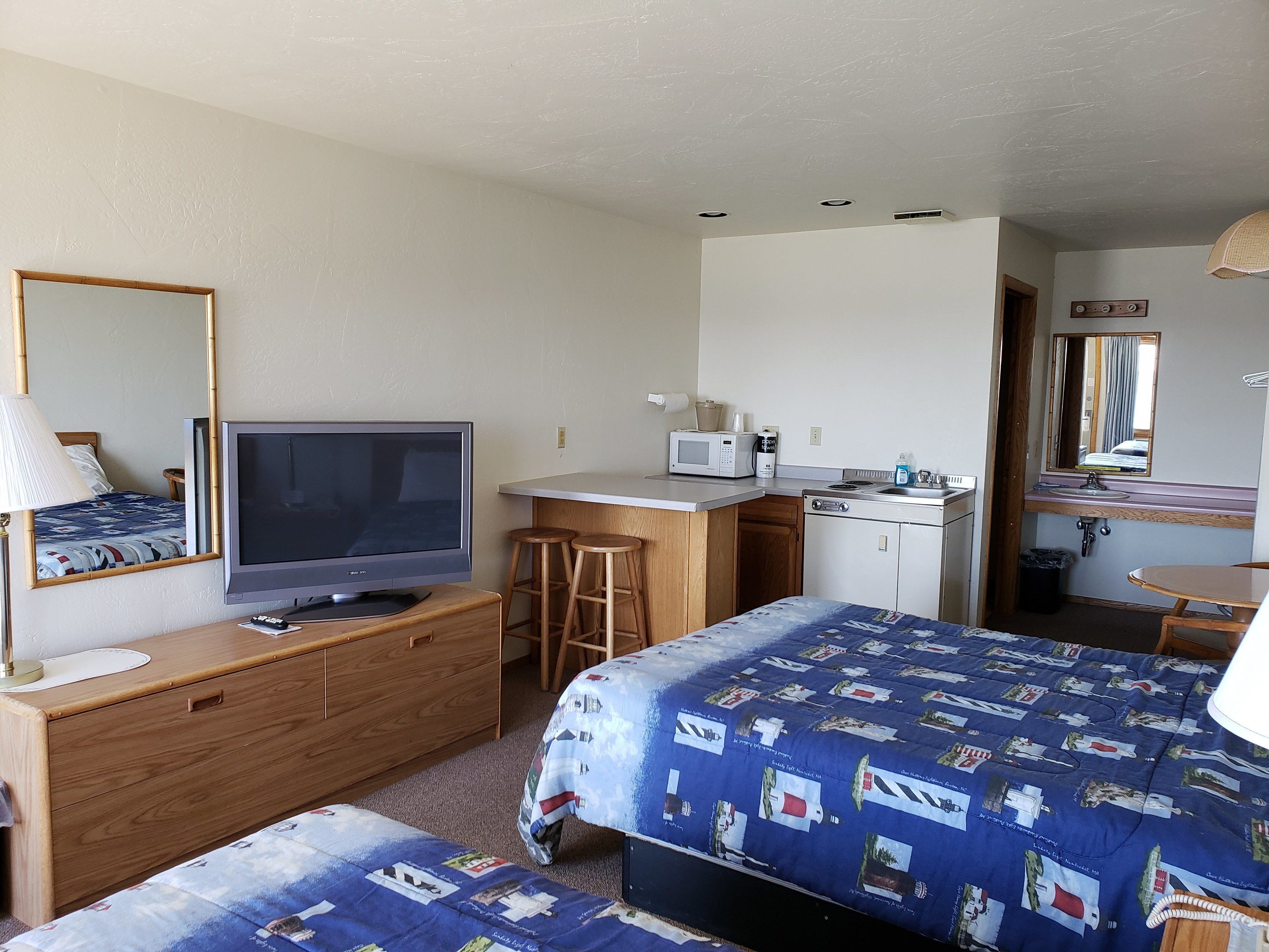 Ein Hotelzimmer mit einem Bett, einem Fernseher, einem Schreibtisch mit einer Mikrowelle, einem Waschbecken und einem Spiegel.
