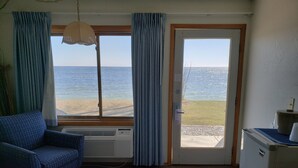 Huoneessa on sänky, sininen nojatuoli, lämmitin, ikkuna, josta on näkymä merelle, ja jääkaappi.