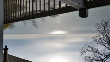 Een uitzicht op een gebouw, met blauwe lucht, zonlicht op het water en een boom op de voorgrond.