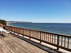Relax on the deck with a bench and table overlooking the beach.