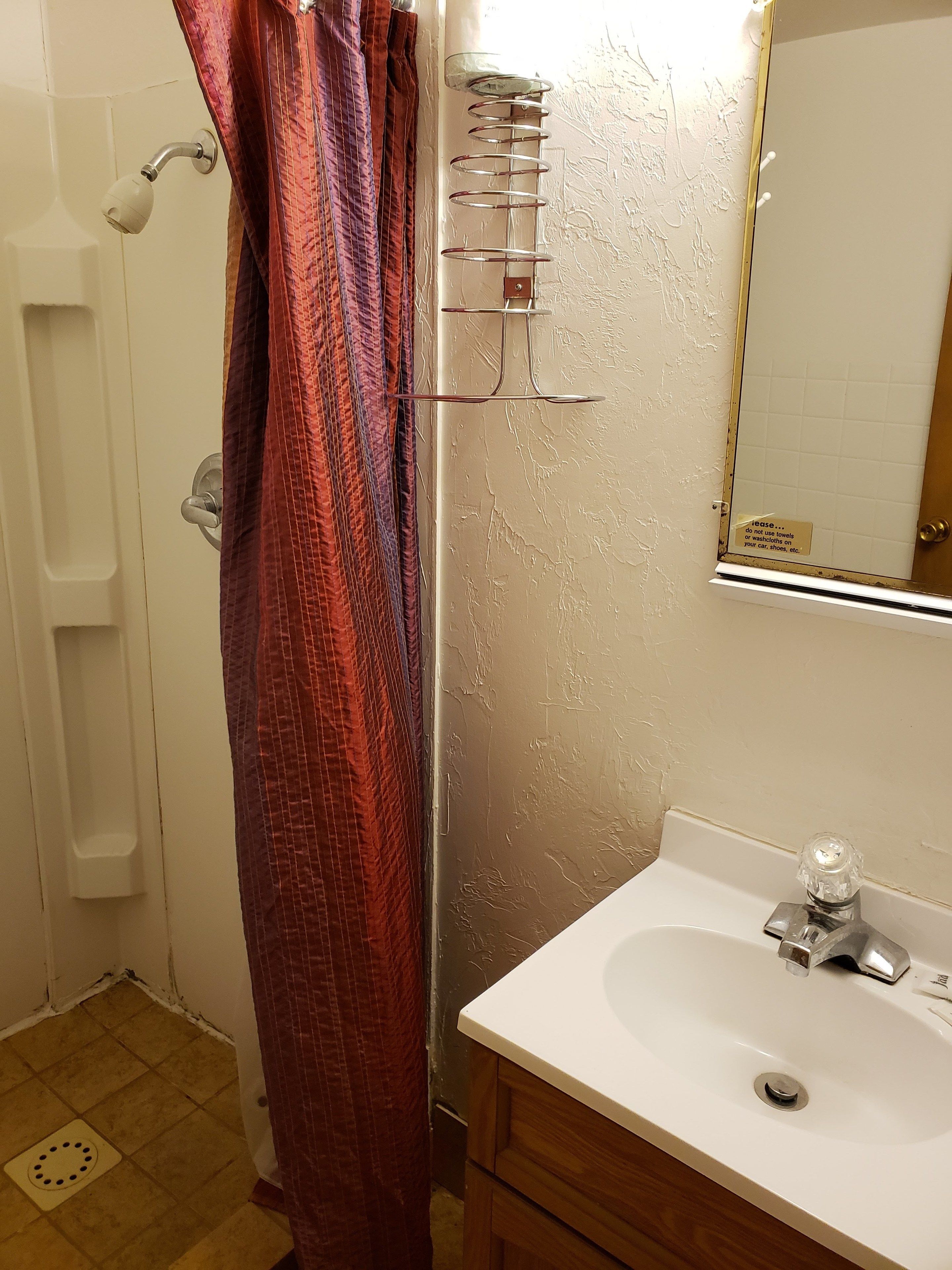 Un baño con ducha, lavamanos y espejo.