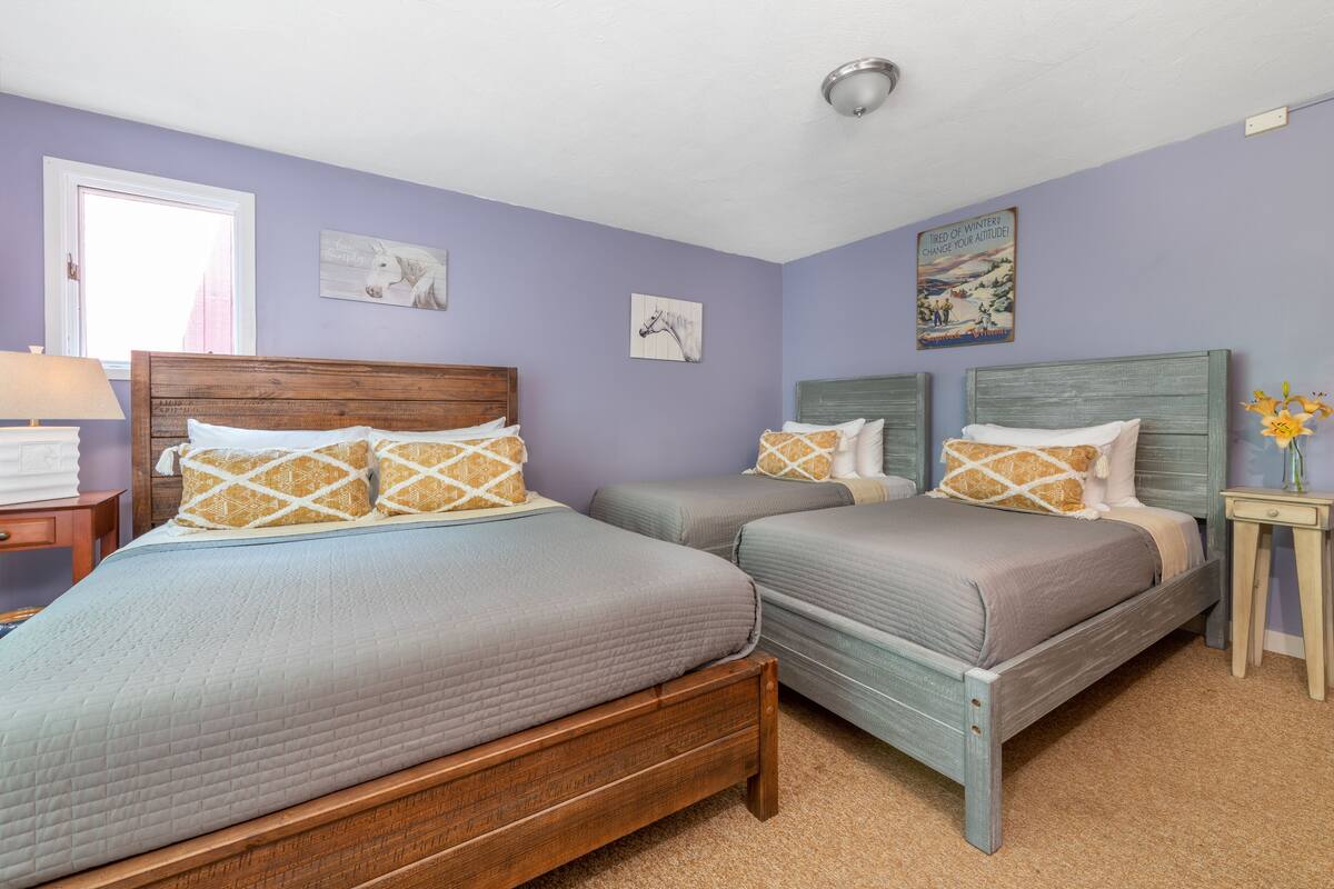 A bedroom with two beds, a nightstand, a lamp, and wall art.