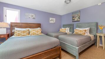A bedroom with two beds, a nightstand, a lamp, and wall art.