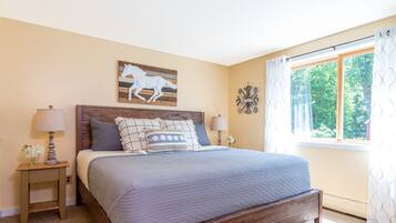 Une chambre à coucher avec un lit en bois, deux tables de chevet, une fenêtre avec des rideaux et une décoration murale représentant un cheval.