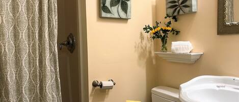 A bathroom with a toilet, sink, towel rack, and a shower curtain.