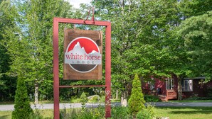 Une enseigne en bois, bordée de rouge, avec le logo de White Horse Lodge.