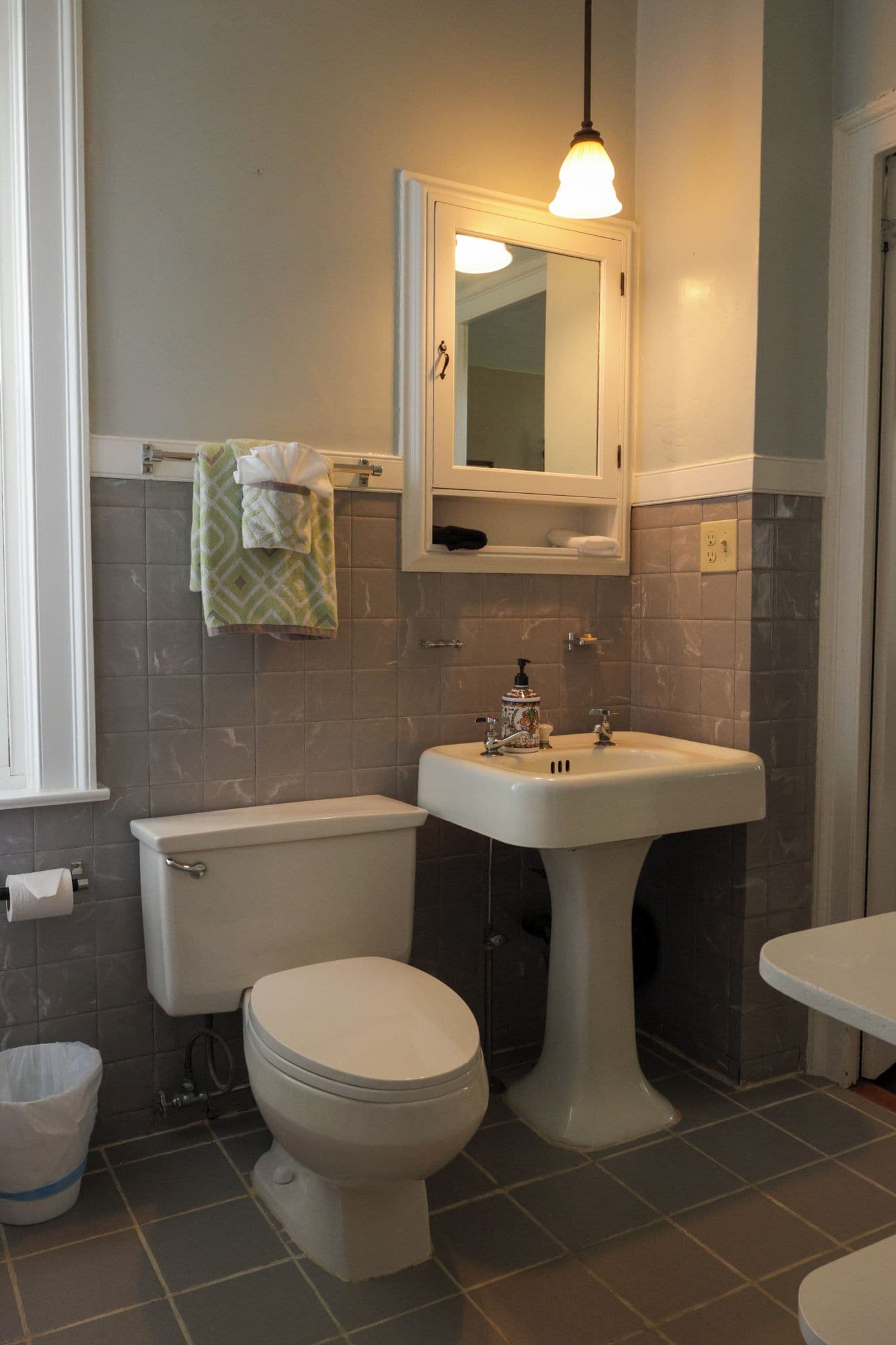 A bathroom with a toilet, sink, and mirror.