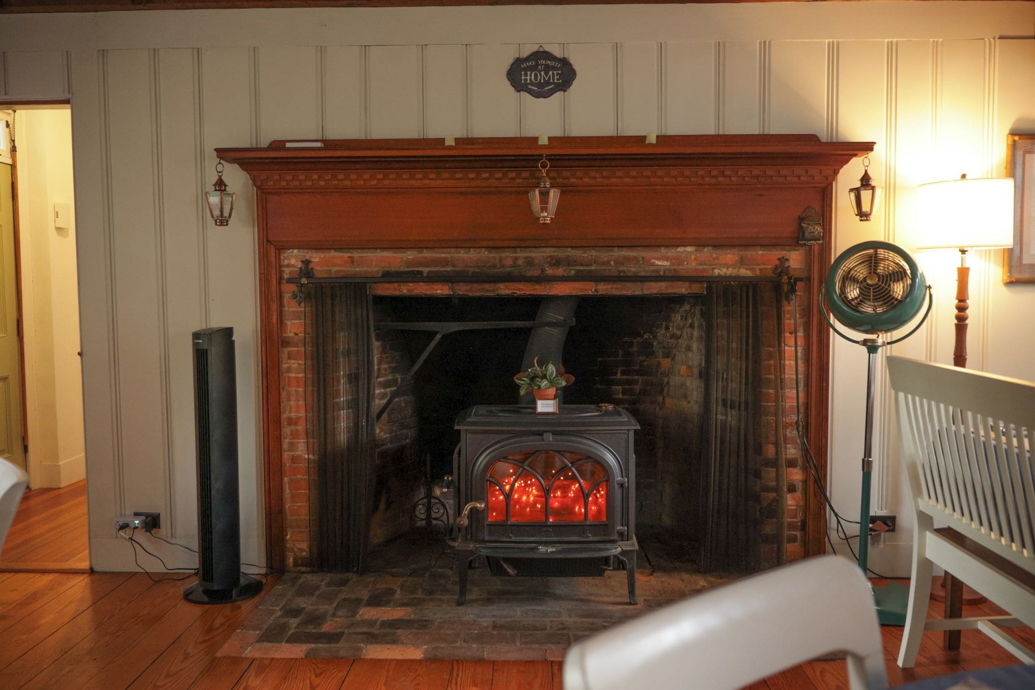 A room with a fireplace, a standing heater, and a fan.
