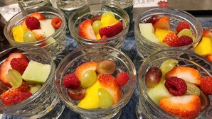 Una mesa con varios recipientes de vidrio pequeños que contienen frutas variadas.