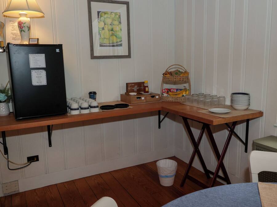 Et tekøkken med køleskab, kaffestation og en skål med frugt.