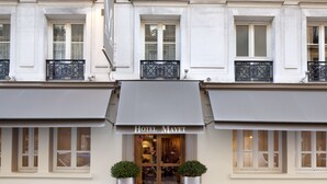 A hotel facade with a classic architectural style, featuring symmetrical windows and decorative iron railings. - Hotel Mayet (Paris)