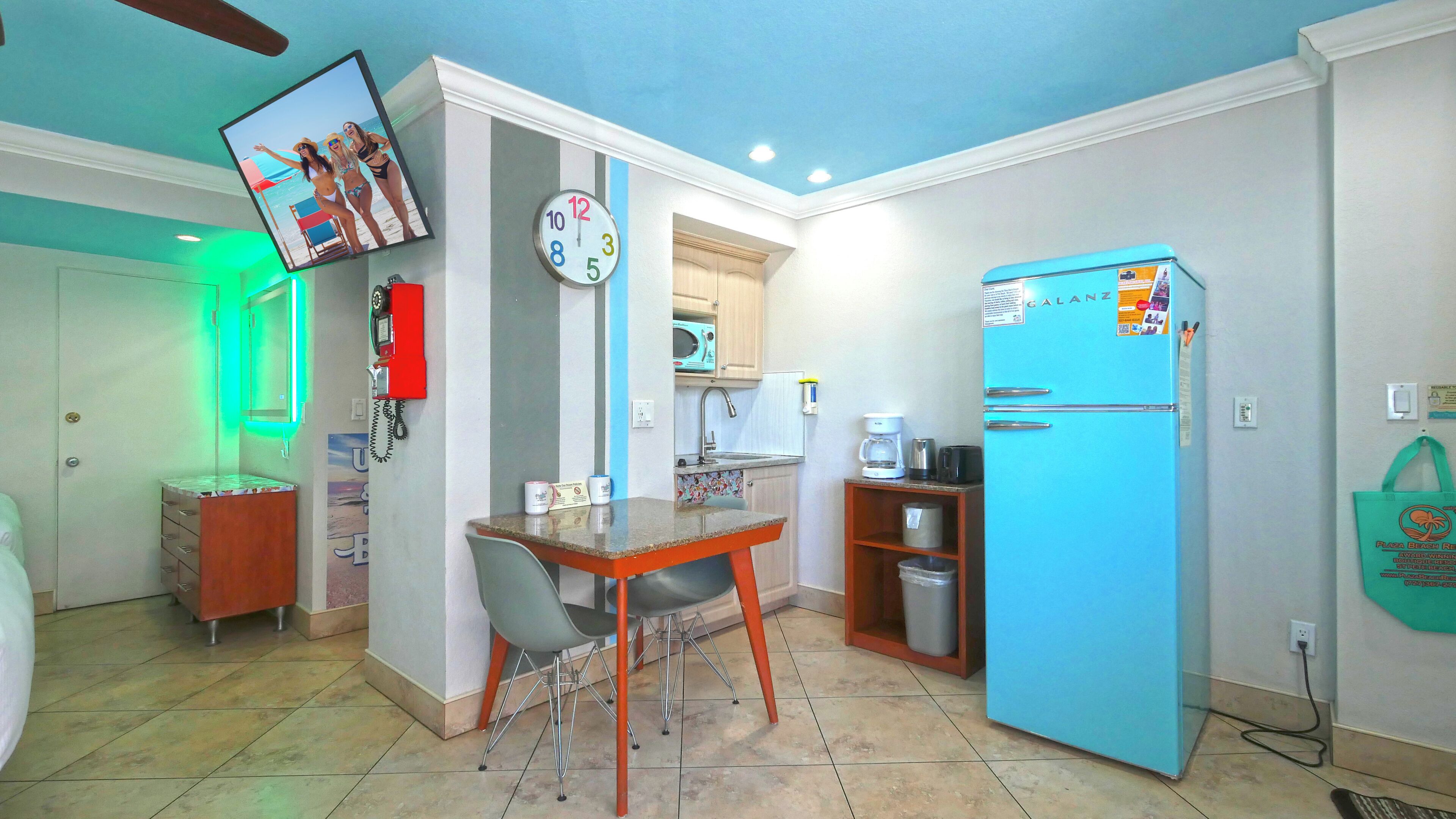 A compact kitchen with a microwave, sink, and a blue refrigerator.