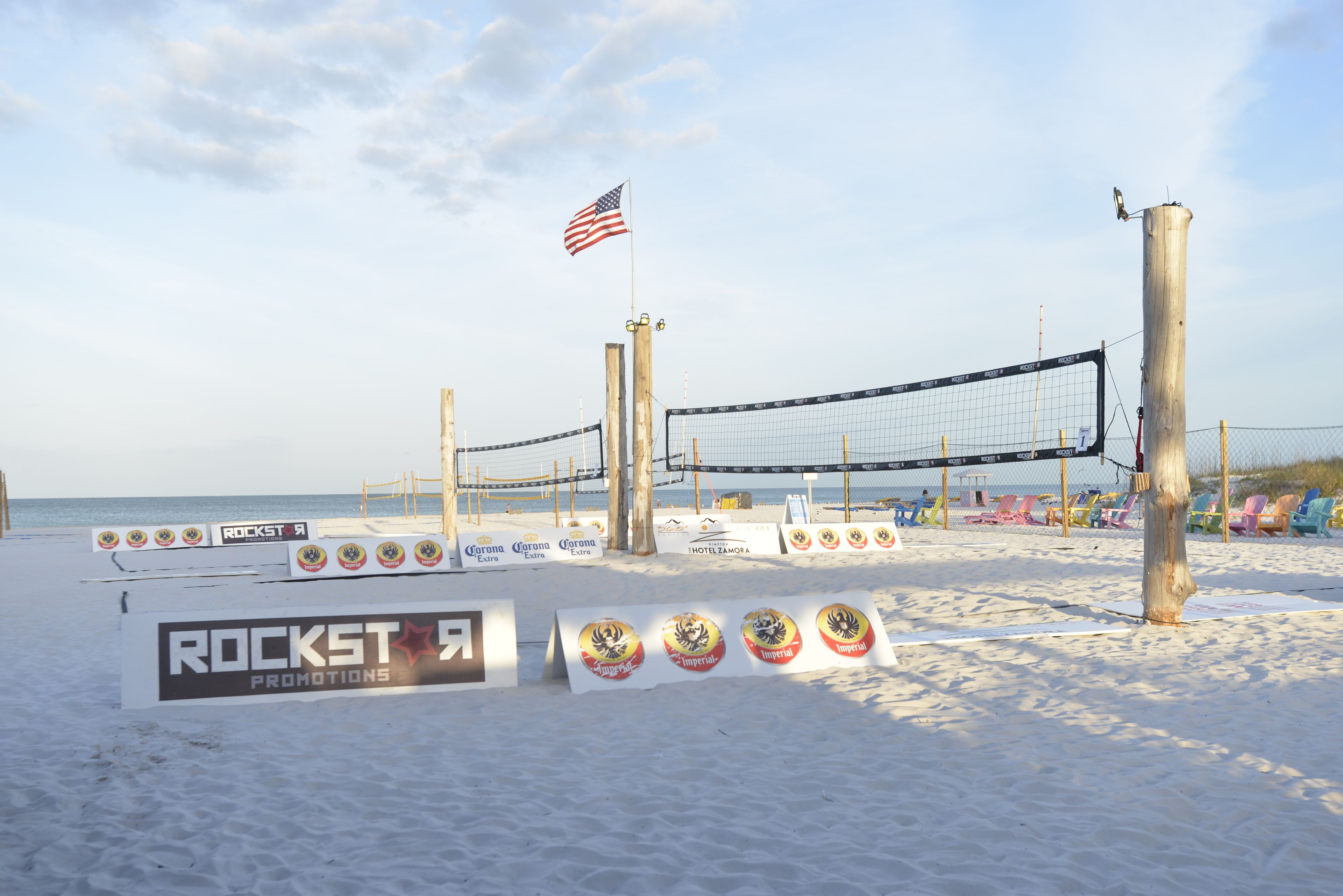 En strandvolleybollplan med nät, amerikansk flagga och reklam­banners.