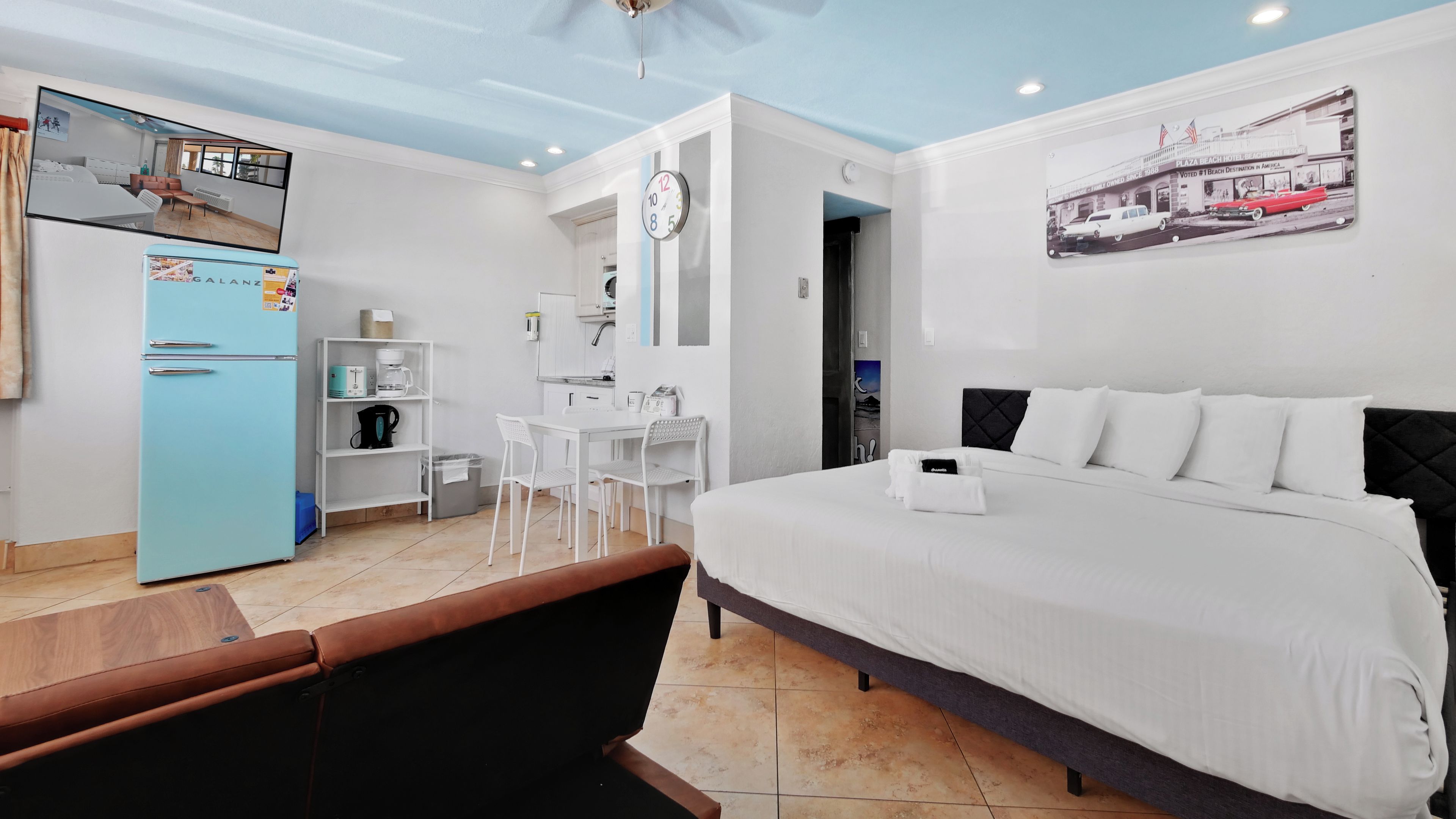 A hotel room with a bed, a kitchenette, a dining area, and a bathroom.