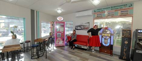 Een café met houten tafels en stoelen, een jukebox en een automaat.