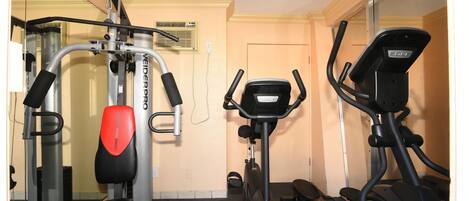 A gym with exercise equipment including a treadmill, stationary bike, and weight machine.