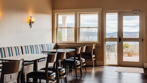 A dining area with a wooden table and chairs, a striped bench, and a view through the door. - Belfast Harbor Inn (Belfast)