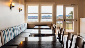A long dining table with benches, a view of a lake and hills, and wall sconces. - Belfast Harbor Inn (Belfast)