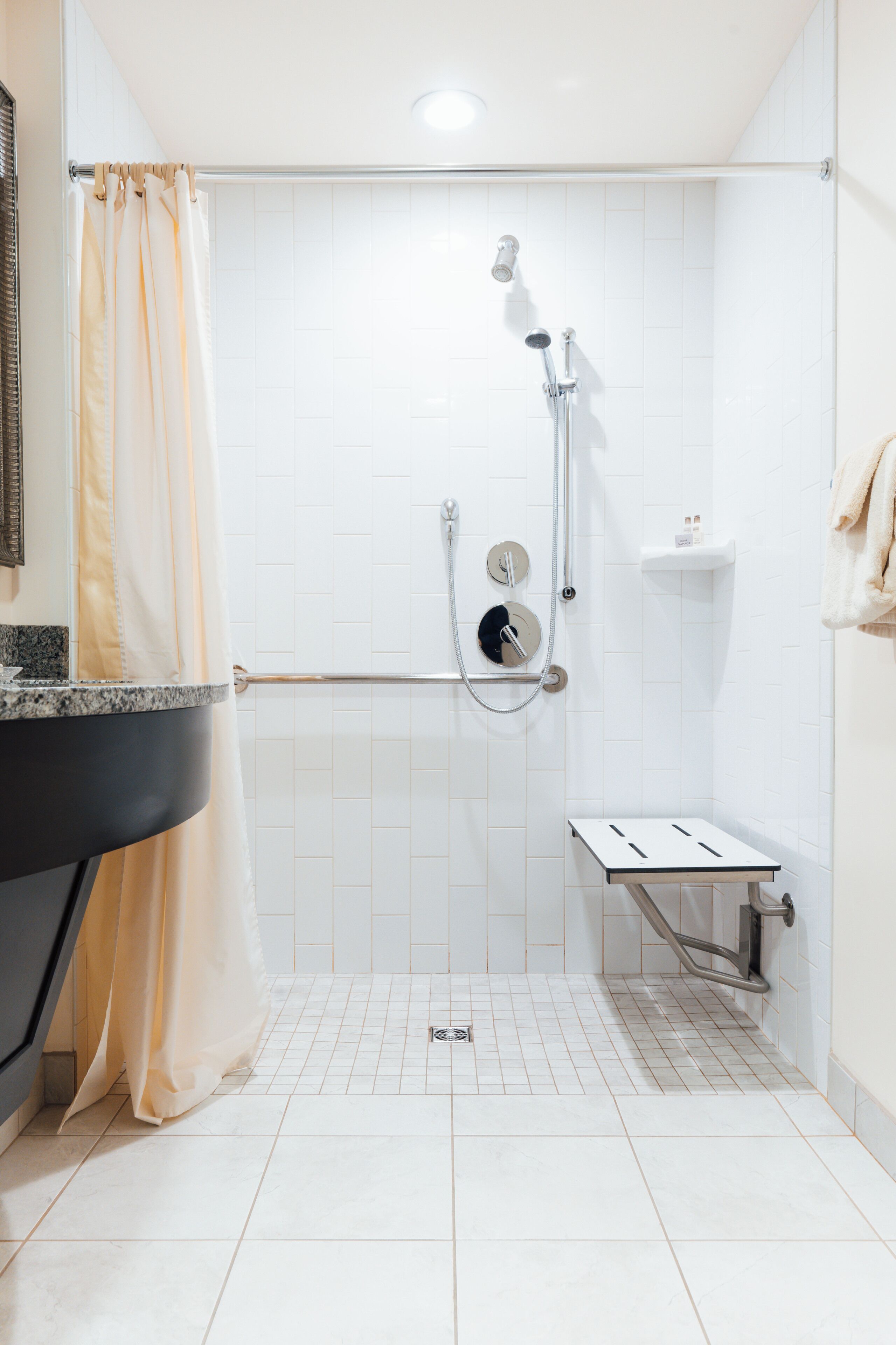 A modern bathroom with a shower, a vanity with a sink, and a towel rack.