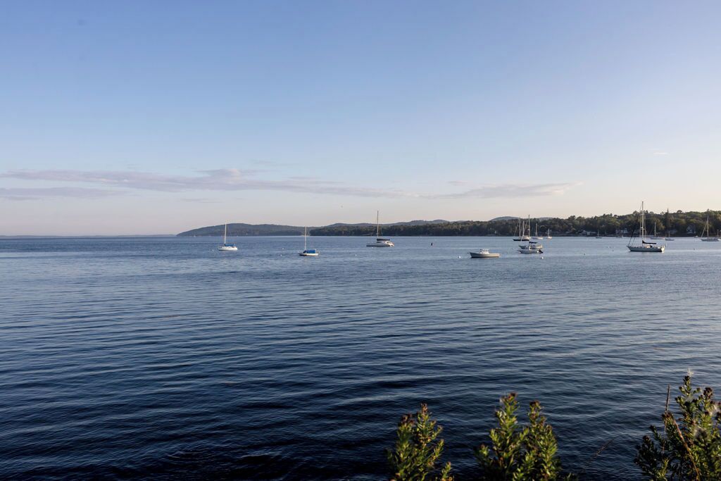 A calm body of water with several boats and a distant shoreline.