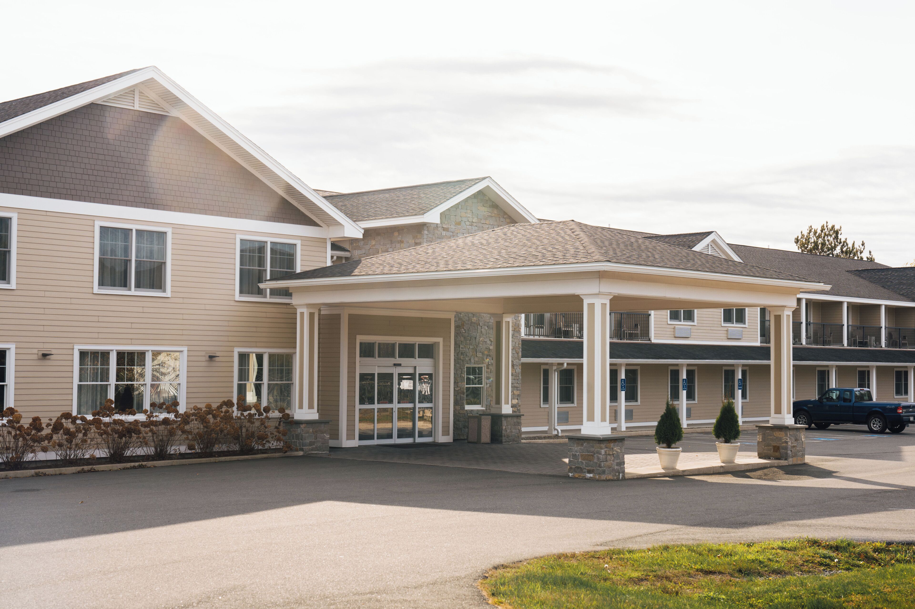 A multi-story hotel with a covered entrance, large windows, and a parking area.