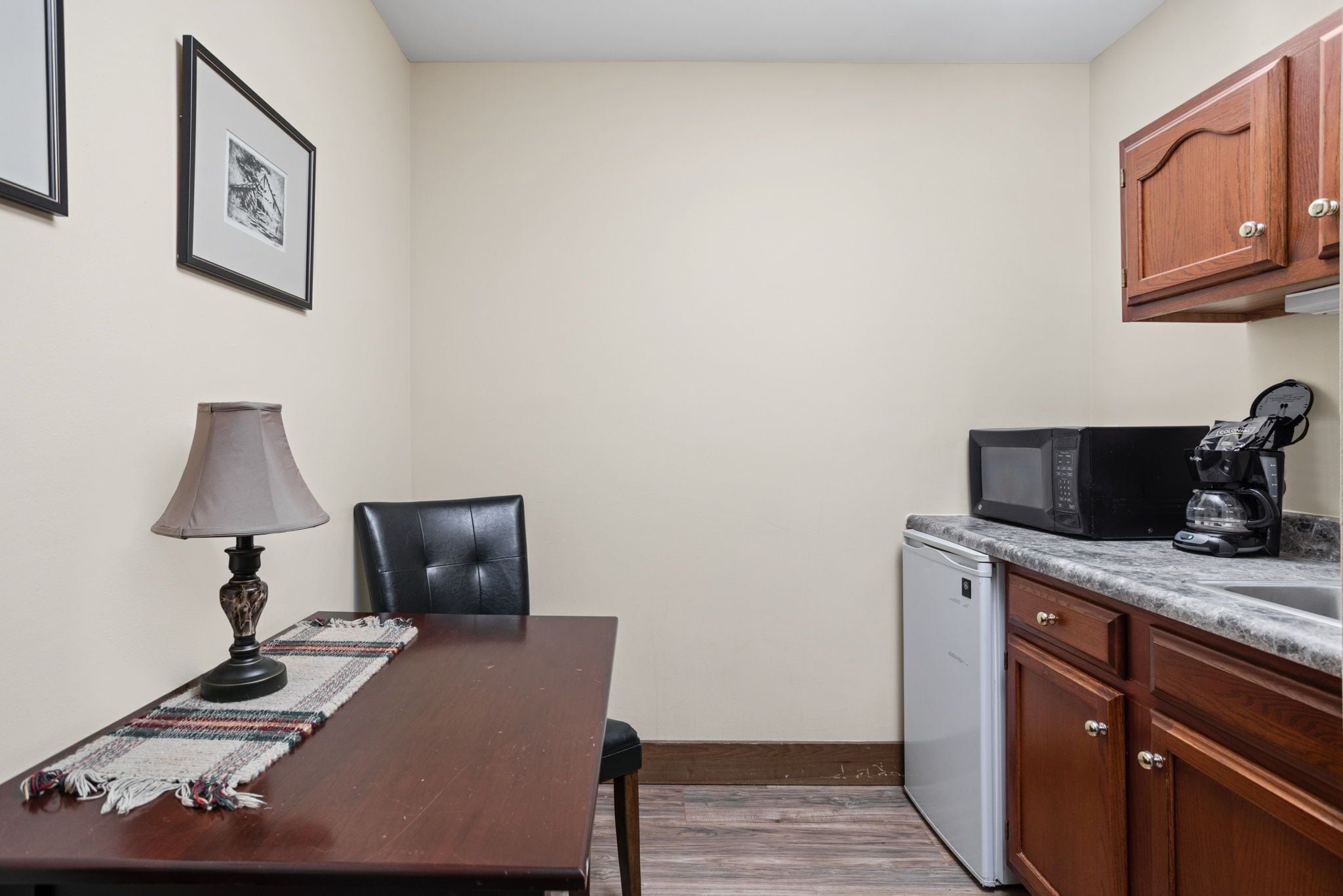 A compact kitchen with a dining table, chairs, a microwave, a coffee maker, and a dishwasher.