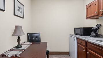 A compact kitchen with a dining table, chairs, a microwave, a coffee maker, and a dishwasher.