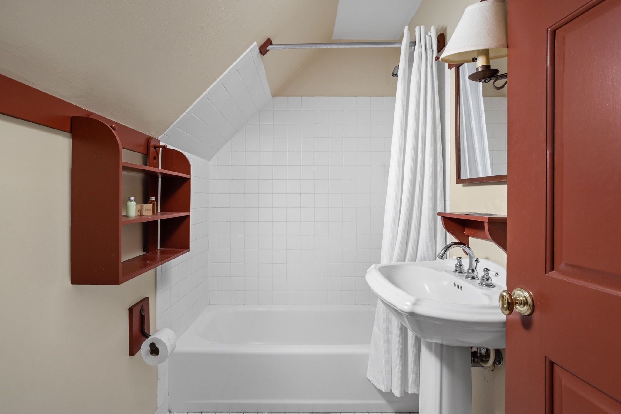Un baño con una bañera blanca, un lavamanos blanco, un espejo y un perchero para toallas.