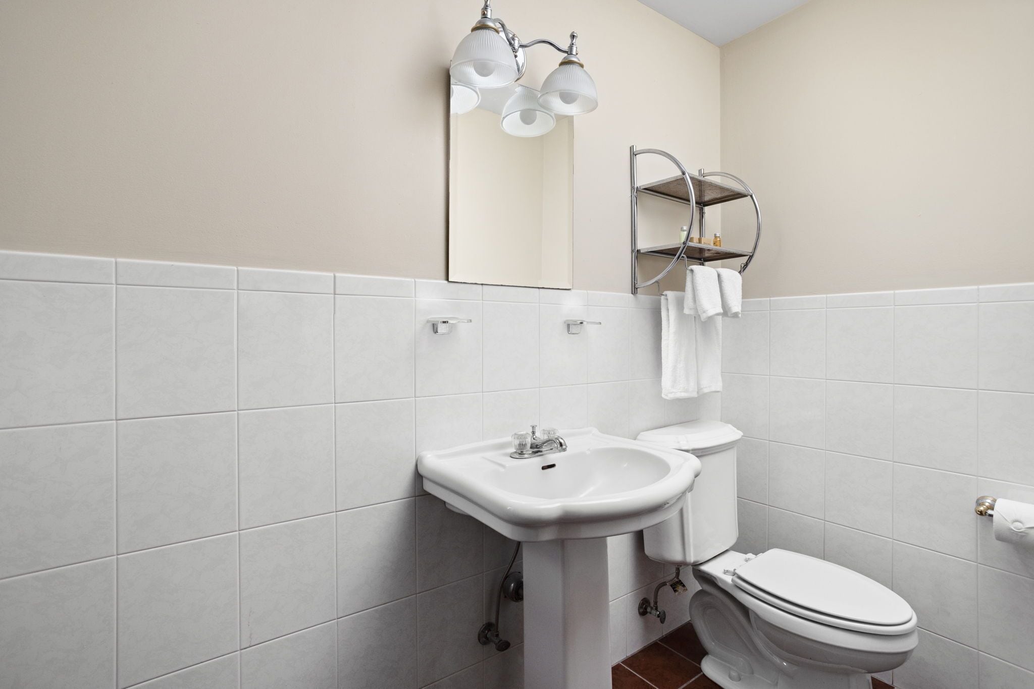 A bathroom with a white sink, a toilet, and a mirror with a towel rack.