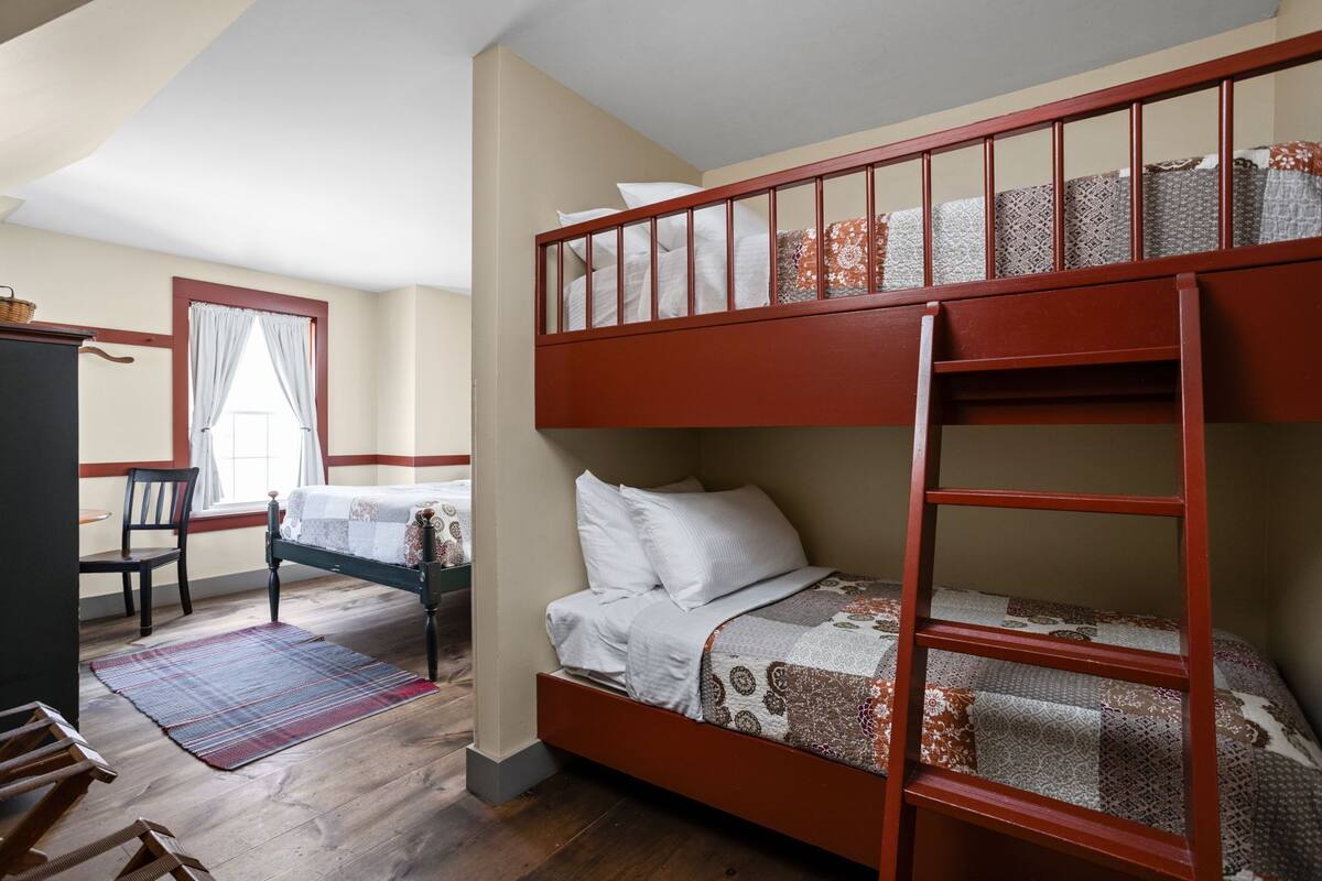 A bunk bed room with a ladder, a desk, and a chair.