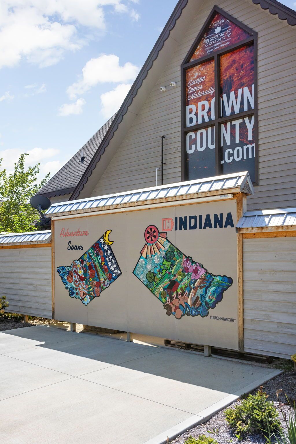 A building with a sign that reads "BROWN COUNTY.COM" and a mural depicting various attractions in Indiana.