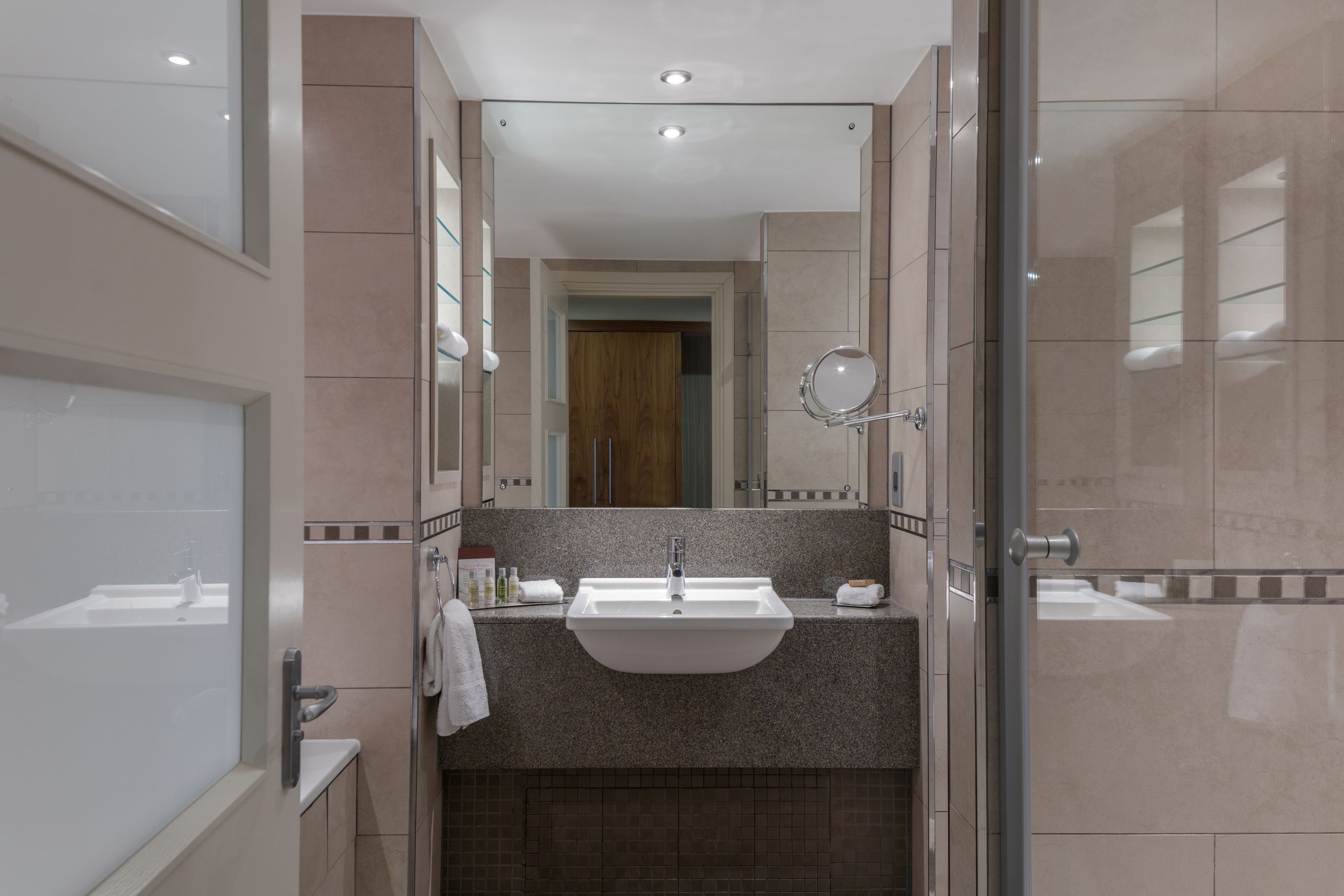 Un baño moderno con un lavamanos grande, un espejo y una cabina de ducha de vidrio.