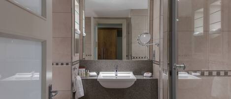 Un baño moderno con un lavamanos grande, un espejo y una cabina de ducha de vidrio.