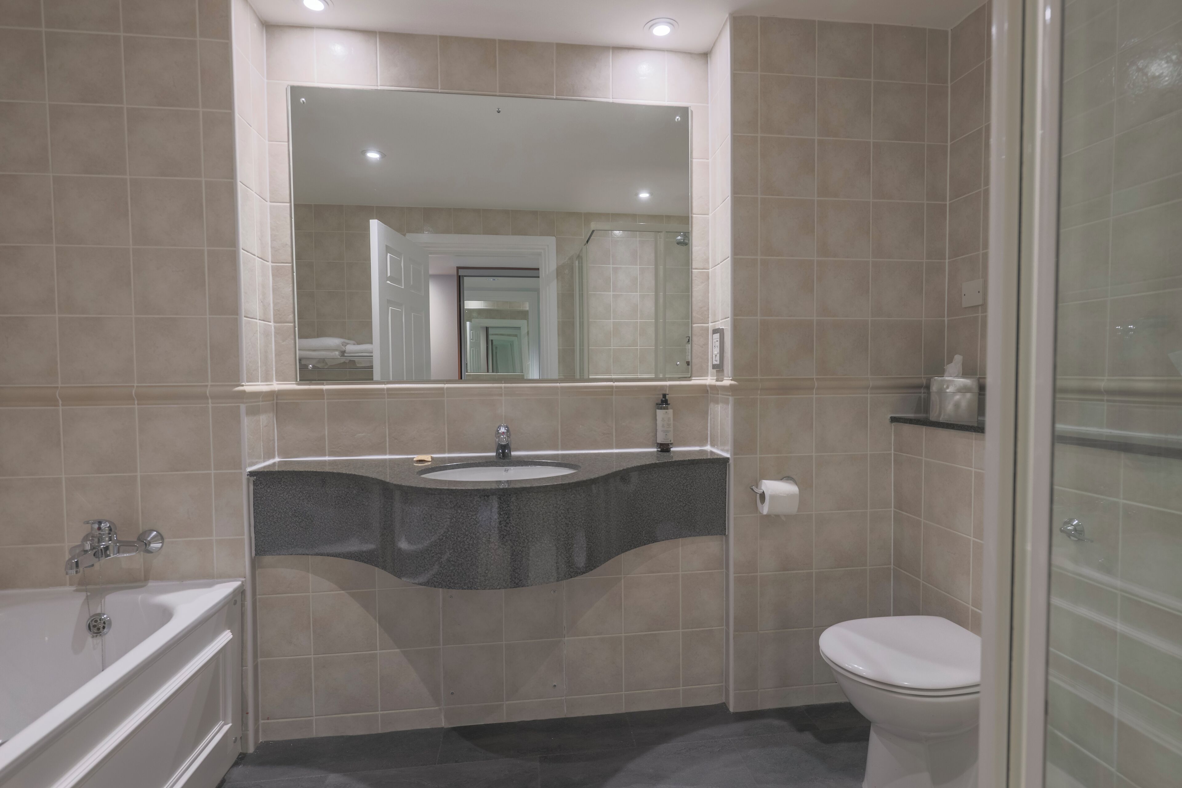 A modern bathroom with a bathtub, sink, and toilet.