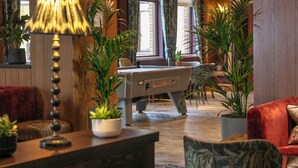 Een gezellige lobby met een pooltafel, comfortabele zitplaatsen en potplanten.