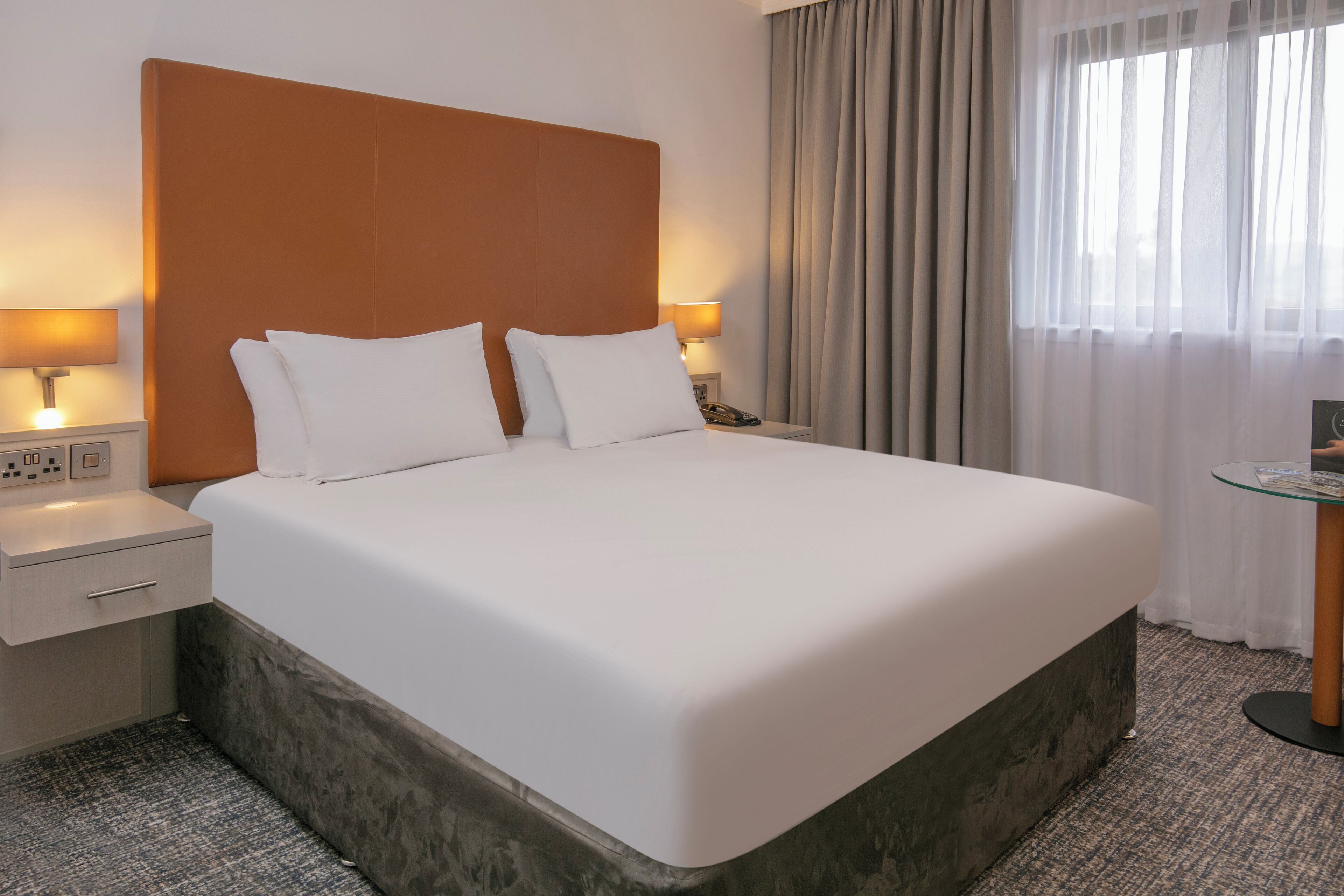 Ein ordentlich bezogenes Bett mit weißen Laken in einem Hotelzimmer.