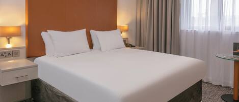 Ein ordentlich bezogenes Bett mit weißen Laken in einem Hotelzimmer.