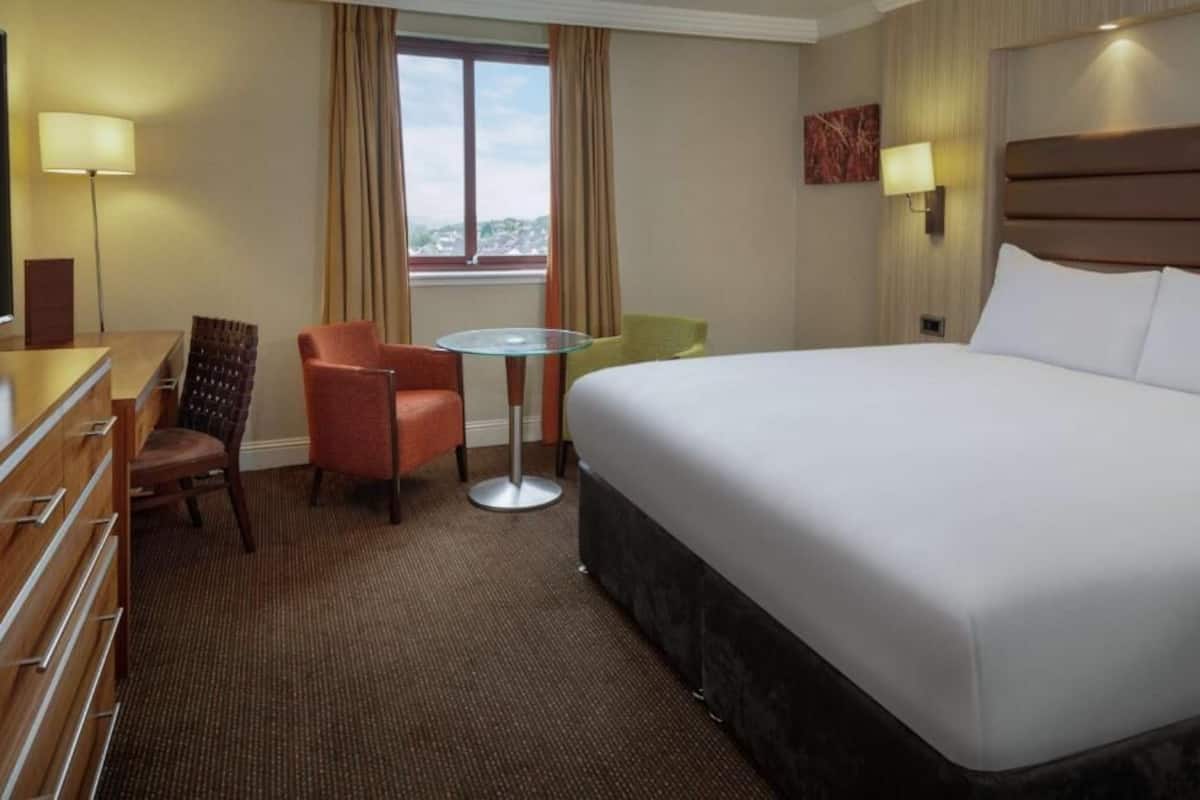 Een hotelkamer met een groot bed, een bureau, een stoel, een kleine tafel en een televisie.