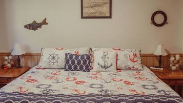 A bedroom with a nautical-themed bedspread, a framed map on the wall, and decorative pillows.