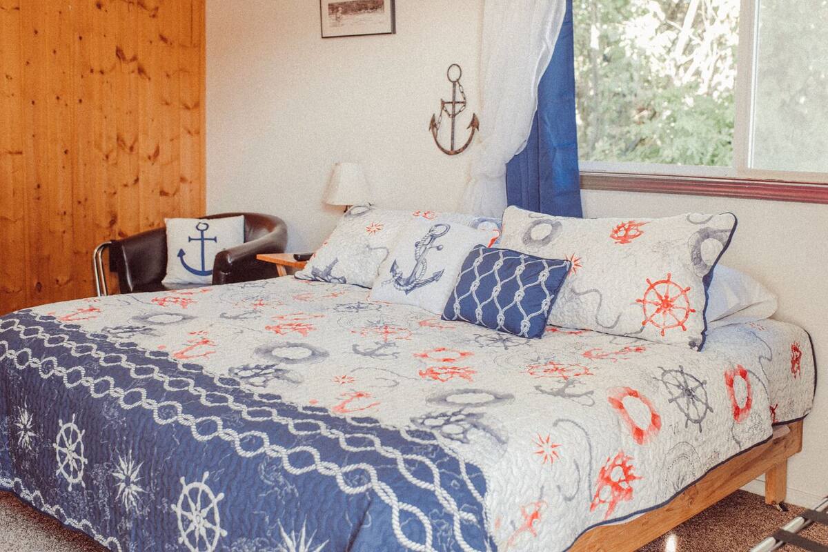 A bedroom with a bed, a chair, a nightstand, and a window with curtains.